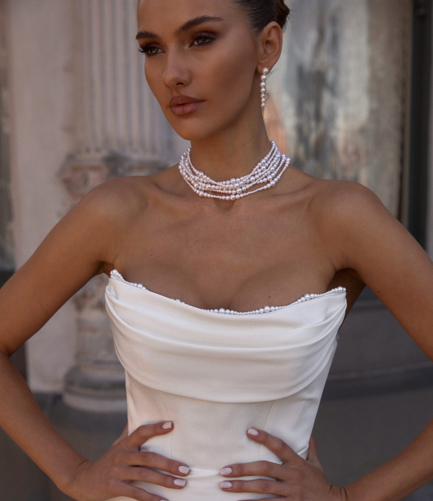 A bride in a strapless draped gown and pearl choker