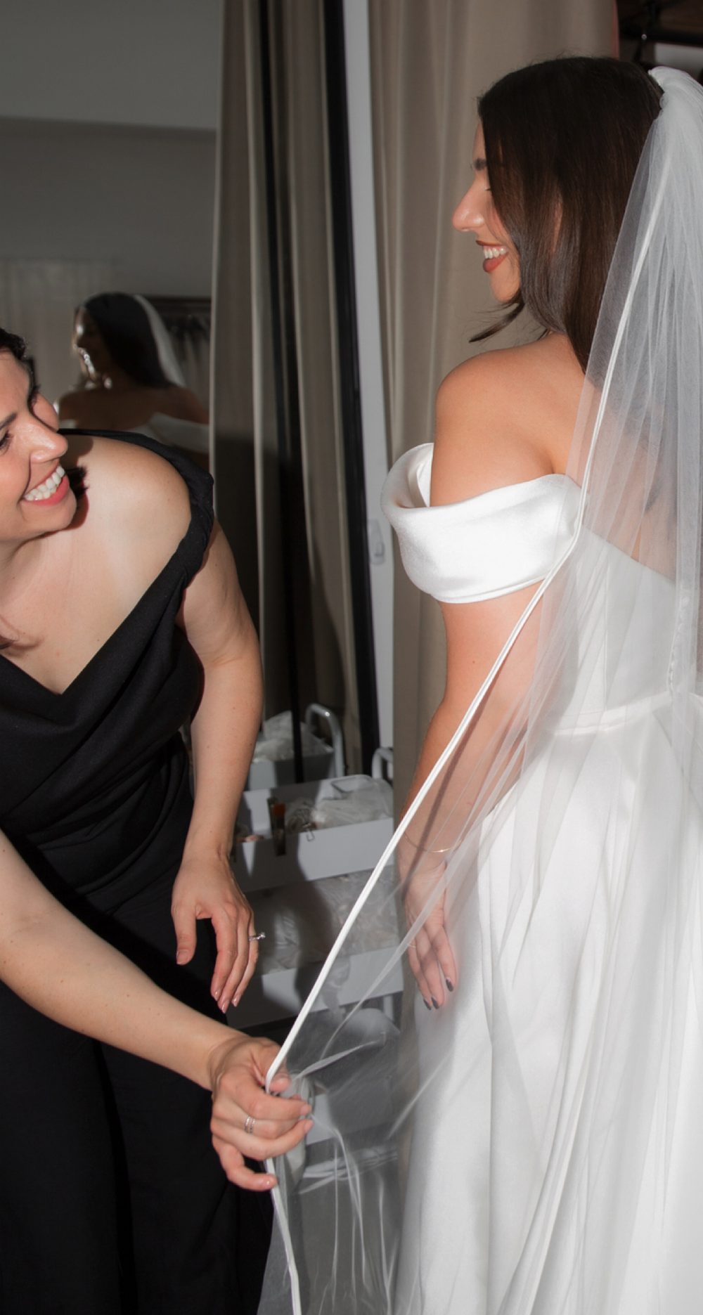 Maggie adjusting a bride’s veil during a fitting